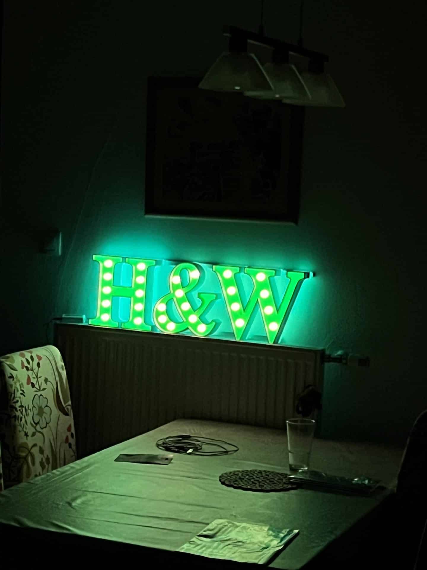 H&W sign lit green on a wall in the evening