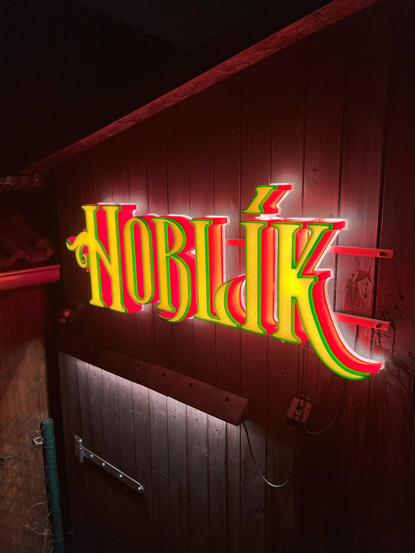 HOBLÍK sign on a wooden shed at night
